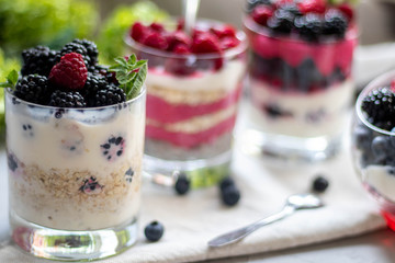 Healthy nutrition Dietary desserts. Glasses are filled with cottage cheese cream, in them chia seeds, raspberries, blueberries, blackberries. Near for background flowers.