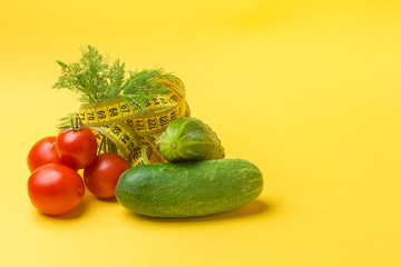 Vegetables and measuring tape on yellow background. The concept of a healthy lifestyle