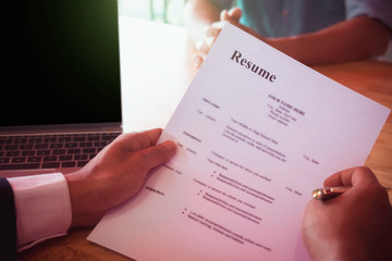 Businessman or HR Manager is reviewing Resume information on his wooden desk. Employment and recruitment concept