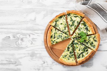 Fototapeta na wymiar Vegetarian spinach pie or tart with feta cheese on white wooden background.