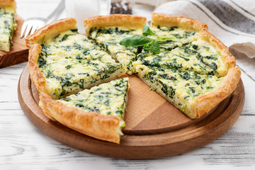 Vegetarian spinach pie or tart with feta cheese on white wooden background. - obrazy, fototapety, plakaty