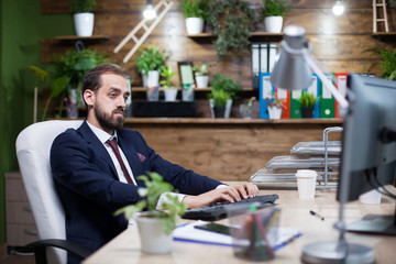 Serious young entrepreneur working on computer in his office