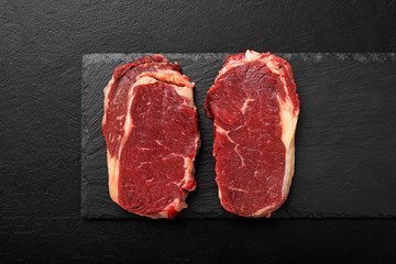Raw meat, beef steak on black background, top view.