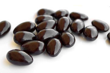 Dark chocolate covered almond candies on white background