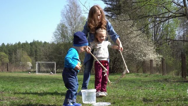 Mother with son and daughter blowing bubbles in park. Gimbal motion