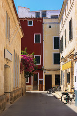 Fototapeta na wymiar Street of Ciutadella town with colorful facades and bougainvillea in bloom, Menorca, Spain