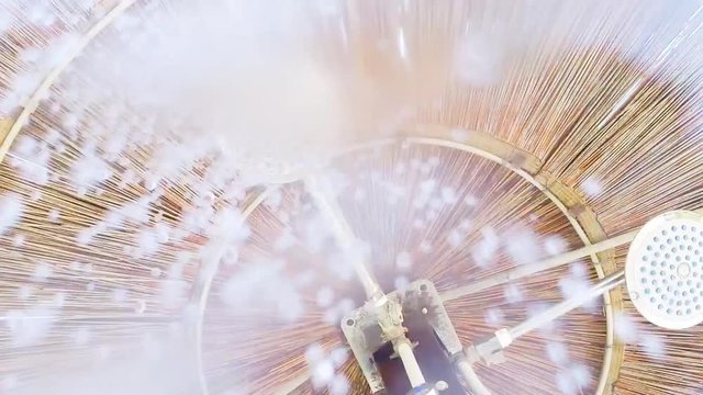 Doccia sotto all'ombrellone di paglia con acqua che cade sulla telecamera.