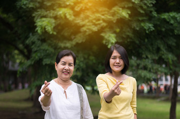 Asian woman hands showing mini heart and relax at public park in the morning together,Happy and smiling,Positive thinking,Healthy and lifestyle concept