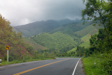 Asphalt road through with sign curves in the mountains.