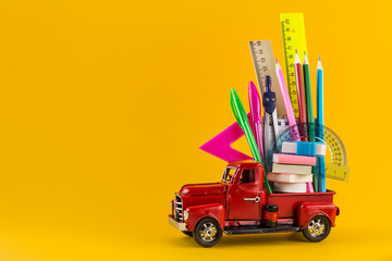 Car delivering School stationery on yellow background.