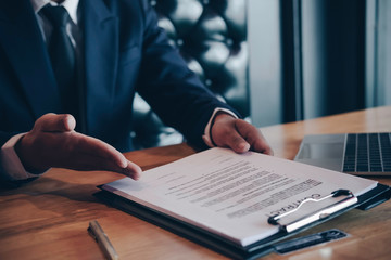 Businessman or HR Manager is reviewing Resume information on his wooden desk. Employment and recruitment concept