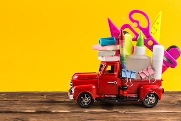 Car delivering School stationery on yellow background © mars58