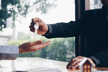 real estate agent holding house key to his client after signing contract,concept for real estate, moving home or renting property