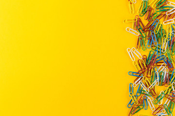 Bunch of colorful paper clips on yellow background