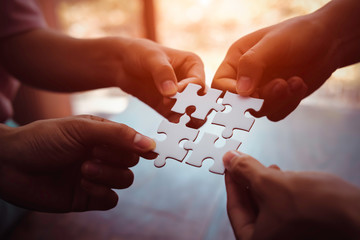 Closeup hand of business people connecting jigsaw puzzle with sunlight effect, Business solutions...