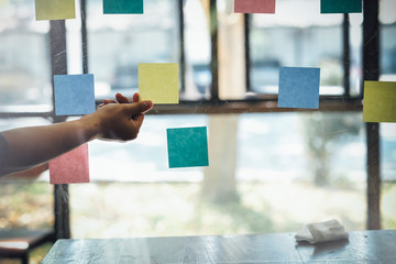 Asian business man hand holding note paper meeting with new startup project use post it notes to...