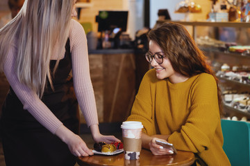 Young pretty woman and waitress in cafe.