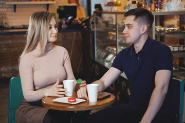 Two cute young students — boy and girl, sit in a cafe.