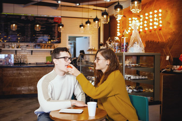 Two cute young men and a girl in a cafe.