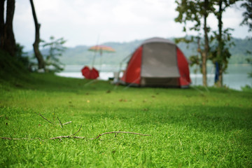 nature landscape red camping tent on campsite under tree on green grass meadow or park with lake or river and tree mountain jungle for picnic travel on family vacation and holiday relax, front focus