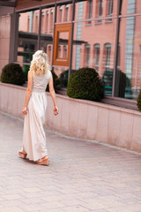 Obraz premium A blonde girl of European appearance in an evening dress poses in the city
