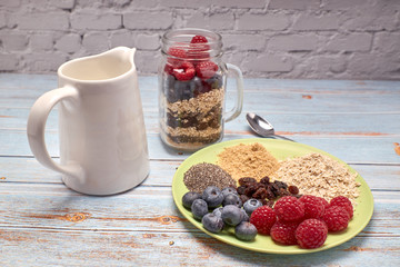 glass jug filled with cereals, raspberries and blueberries