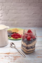 glass jug filled with cereals, raspberries and blueberries