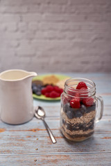 glass jug filled with cereals, raspberries and blueberries