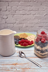 glass jug filled with cereals, raspberries and blueberries