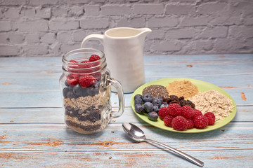 glass jug filled with cereals, raspberries and blueberries