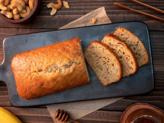 Homemade banana bread pound sliced with cashew nuts and honey on wooden table.