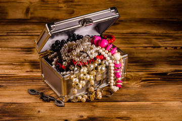 Aluminium case full of different jewelry on wooden table