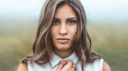 Fototapeta premium Dramatic portrait of a girl with frightened eyes against the morning mist. Close-up looking at the camera.