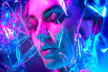 Schilderijen op glas Mannequin vrouw in kleurrijke felle neonlichten poseren in studio door transparante film. Portret van mooi sexy meisje in UV. Art design kleurrijke make-up © Subbotina Anna