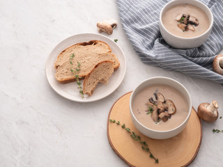 Mushroom cream soup in white bowl with bread on the table. Delicious cream soup with champignon mushrooms.