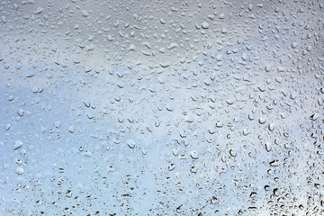 water drops on glass against the sky and trees.