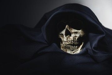 Closeup photo an old skull covered in black robe