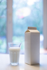 Carton box and glass of milk on table in kitchen