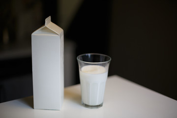 Carton box and glass of milk on table in kitchen