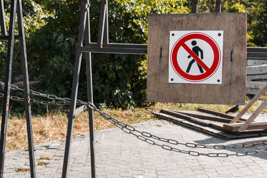 Restricted Area For man sign Is hanging on a black iron fence with a chain near the construction site. Strikethrough human silhouette on red circle. No trespassing sign near a dangerous site 