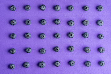 Colorful fruit pattern of blueberries on purple background. Top view.