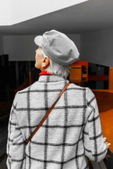 fashionable caucasian woman in a cap and jacket goes down the escalator to the underground parking and looks up, vertical image.