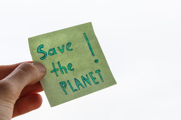 fingers of a teenager hold sticker with call to save the planet. handwritten inscription save the planet in the male hand. 