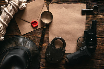 Top secret information mockup, leather hat, weapon, magnifying glass and rope on a wooden table of...
