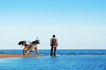 Biker with a motorcycle on the beach. The object is in focus, the background is blurred.