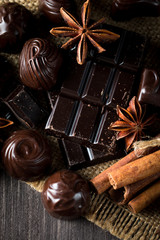 Assortment of dark, white and milk chocolate stack, chips. Chocolate and coffee beans on rustic wooden sacking background. Spices, cinnamon. Selective macro focus. Chocolates background. Sweets