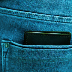 Black men's wallet from high-quality genuine leather lies in the back pocket of men's blue jeans,...