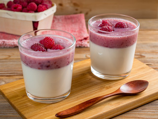 Two cups of panna cotta with raspberry and raspberry sauce on wooden background. Selective focus