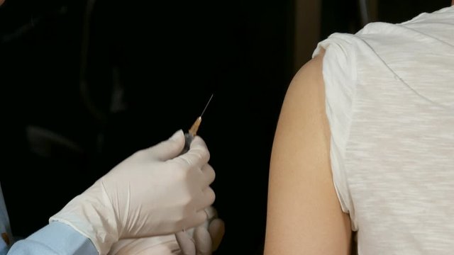 Doctor injecting flu vaccine to patient's arm in local hospital