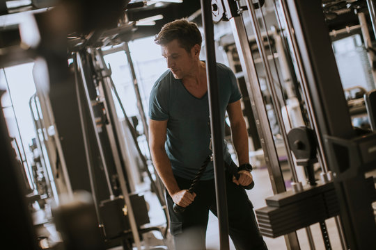 Young sporty man working out on pull-down machine in gym